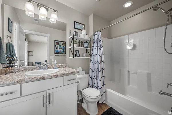 Bathroom featuring a white vanity with slab cabinet doors and brushed nickel hardware, a speckled countertop, an oval undermount sink with a polished chrome faucet, and a large wall mirror