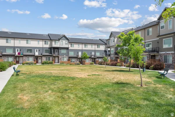 Spacious central green space featuring a manicured lawn, established landscaping, and paved walkways