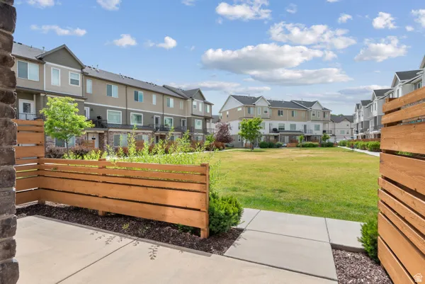 Private patio with concrete pavers and a slatted wood fence overlooking a manicured green space