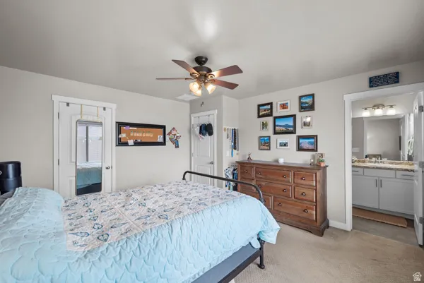 Carpeted room featuring a ceiling fan with integrated lighting, a door with white trim, and direct access to a bathroom