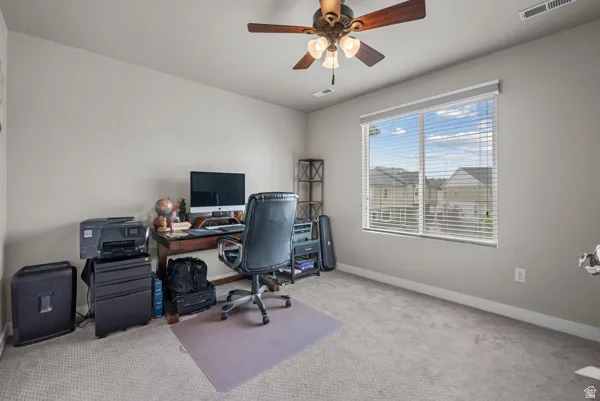 Spacious room featuring neutral carpeting, light-toned walls, and a ceiling fan with integrated lighting