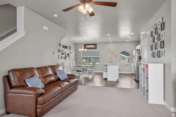 Open-concept living space featuring a ceiling fan, recessed lighting, and wood-finish flooring in the kitchen and dining areas