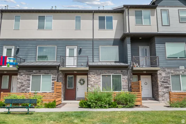 Contemporary townhome with a multi-textured facade featuring stone veneer, horizontal siding, and stucco