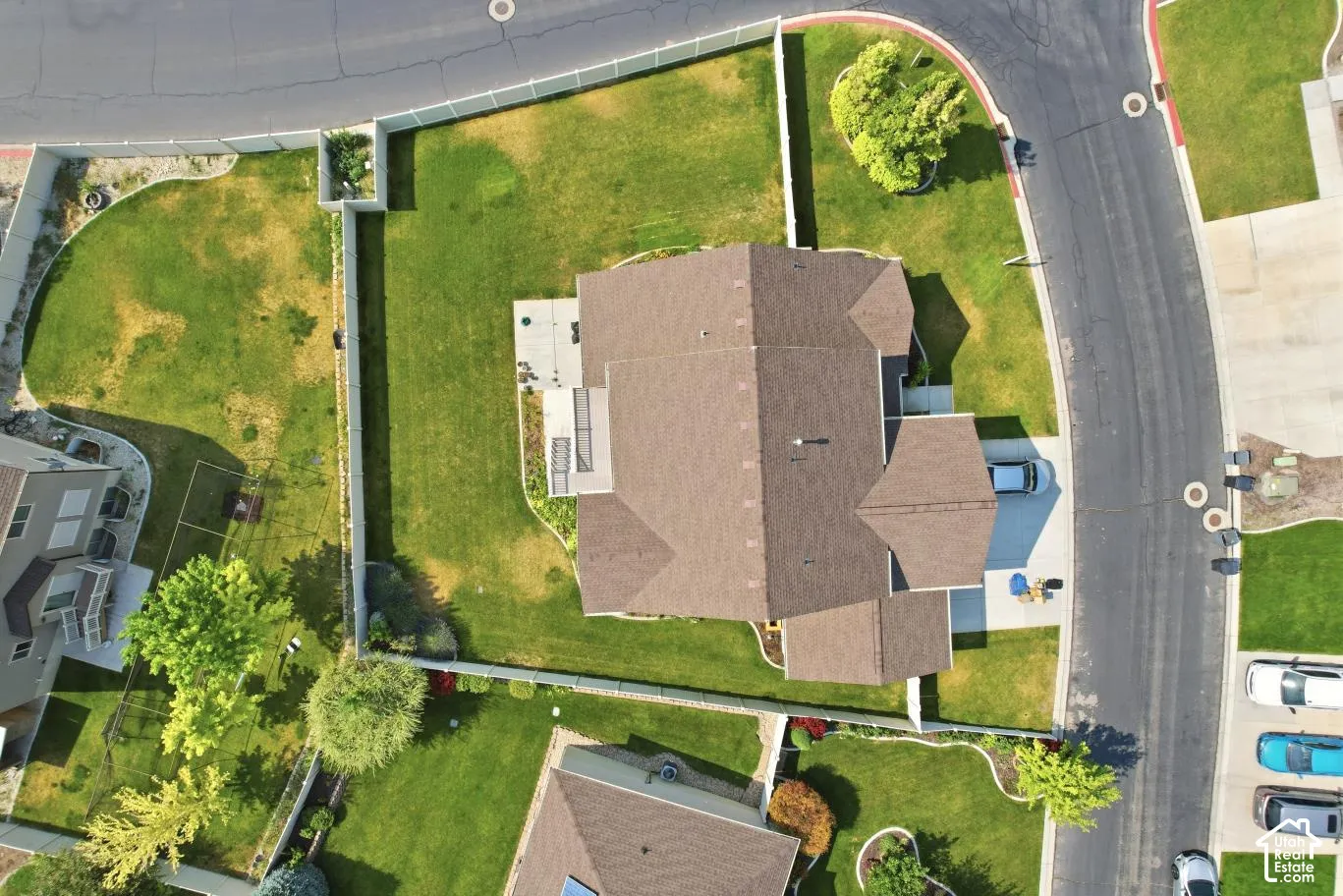 Expansive property featuring a brown shingle roof, a paved driveway, and a concrete patio