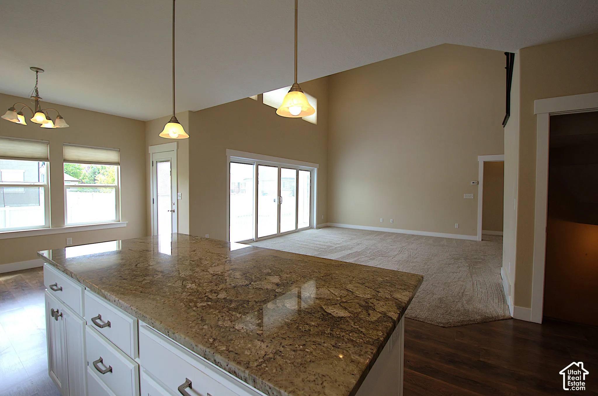 Kitchen island with a polished granite countertop, white cabinetry, and brushed nickel hardware