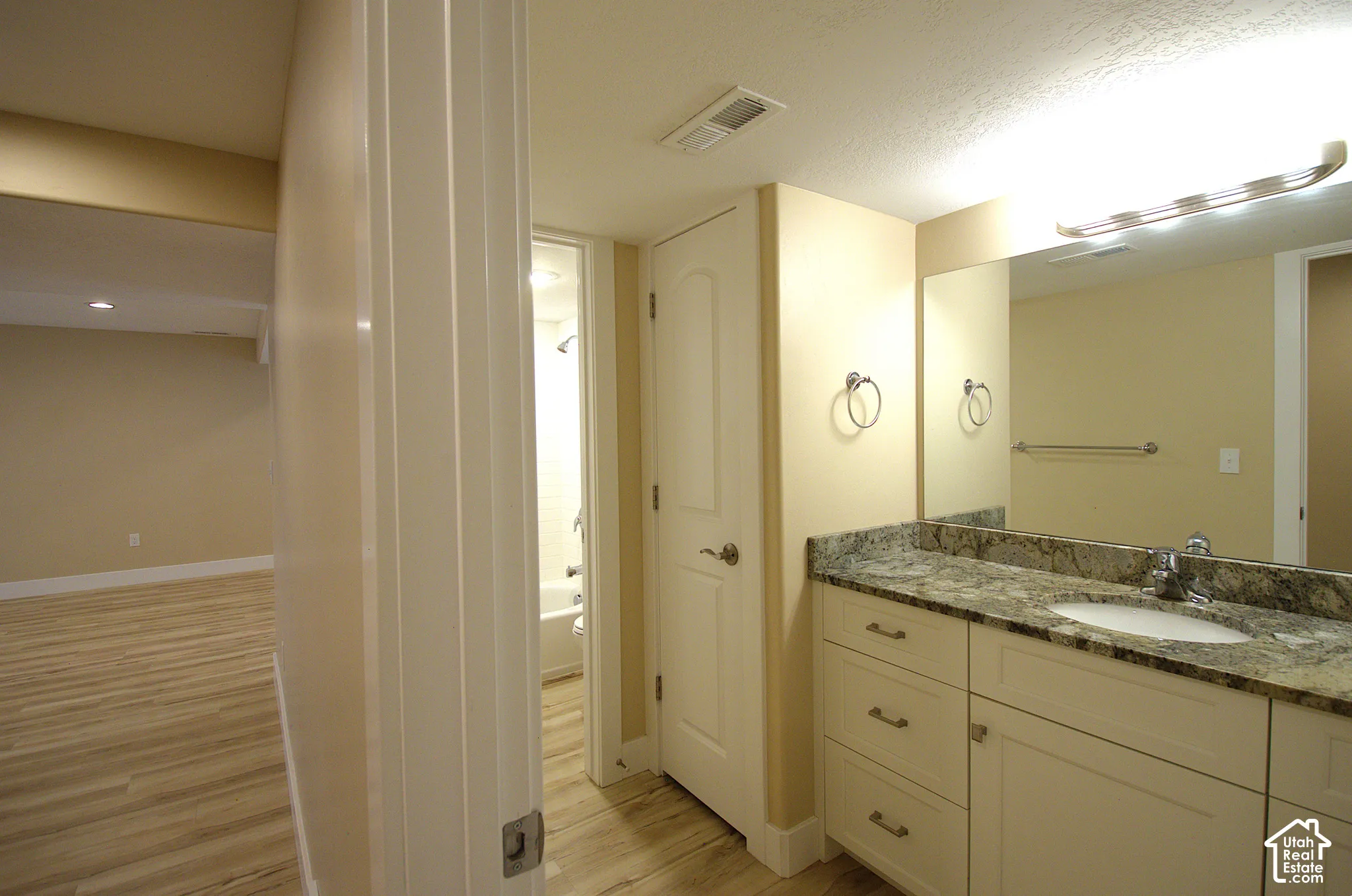 Bathroom vanity featuring a single basin sink, speckled countertop, and white cabinetry with drawer pulls