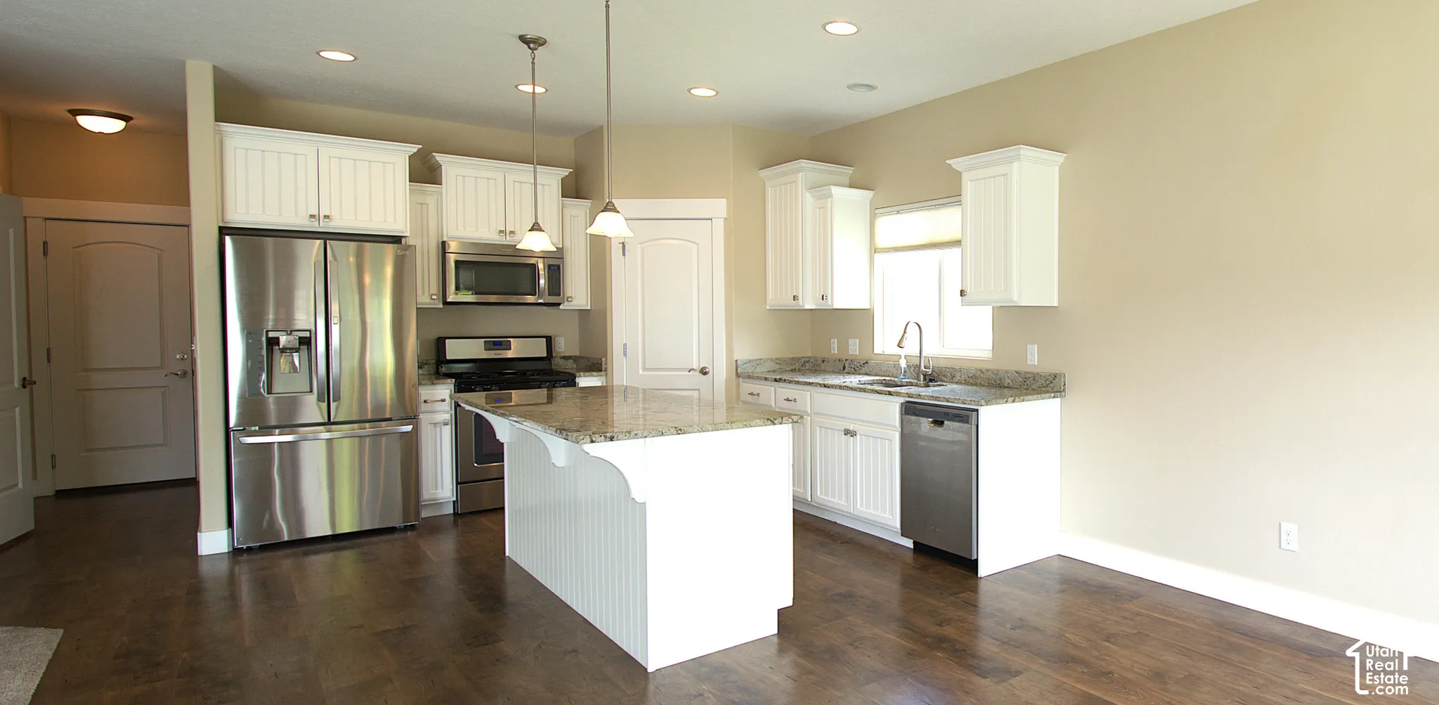 Kitchen featuring white cabinetry, stainless steel appliances, a central island with a granite countertop, and wood-finish flooring