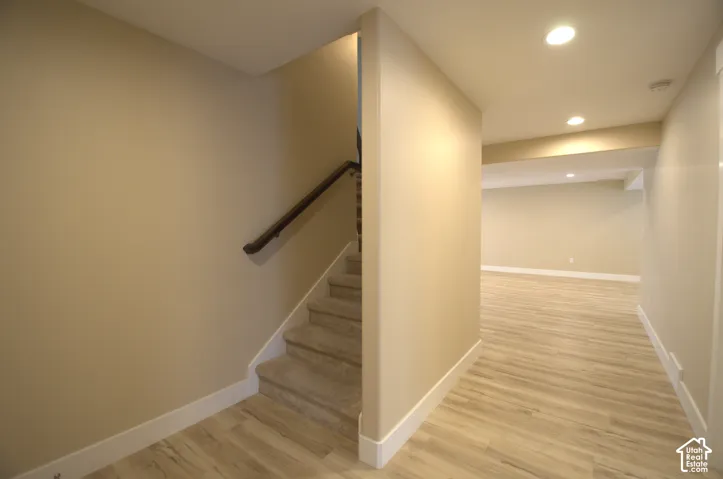 Lower level featuring wood-finish flooring, recessed lighting, and a carpeted staircase with a dark wood handrail