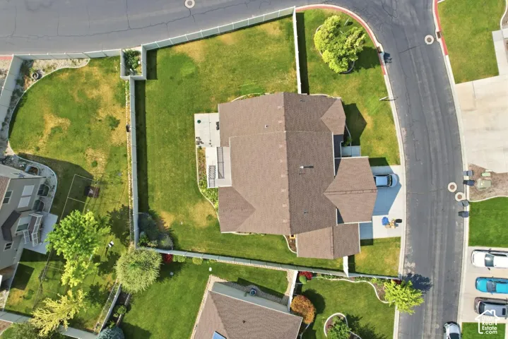 Expansive property featuring a brown shingle roof, a paved driveway, and a concrete patio