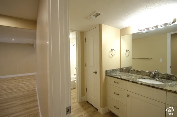 Bathroom vanity featuring a single basin sink, speckled countertop, and white cabinetry with drawer pulls