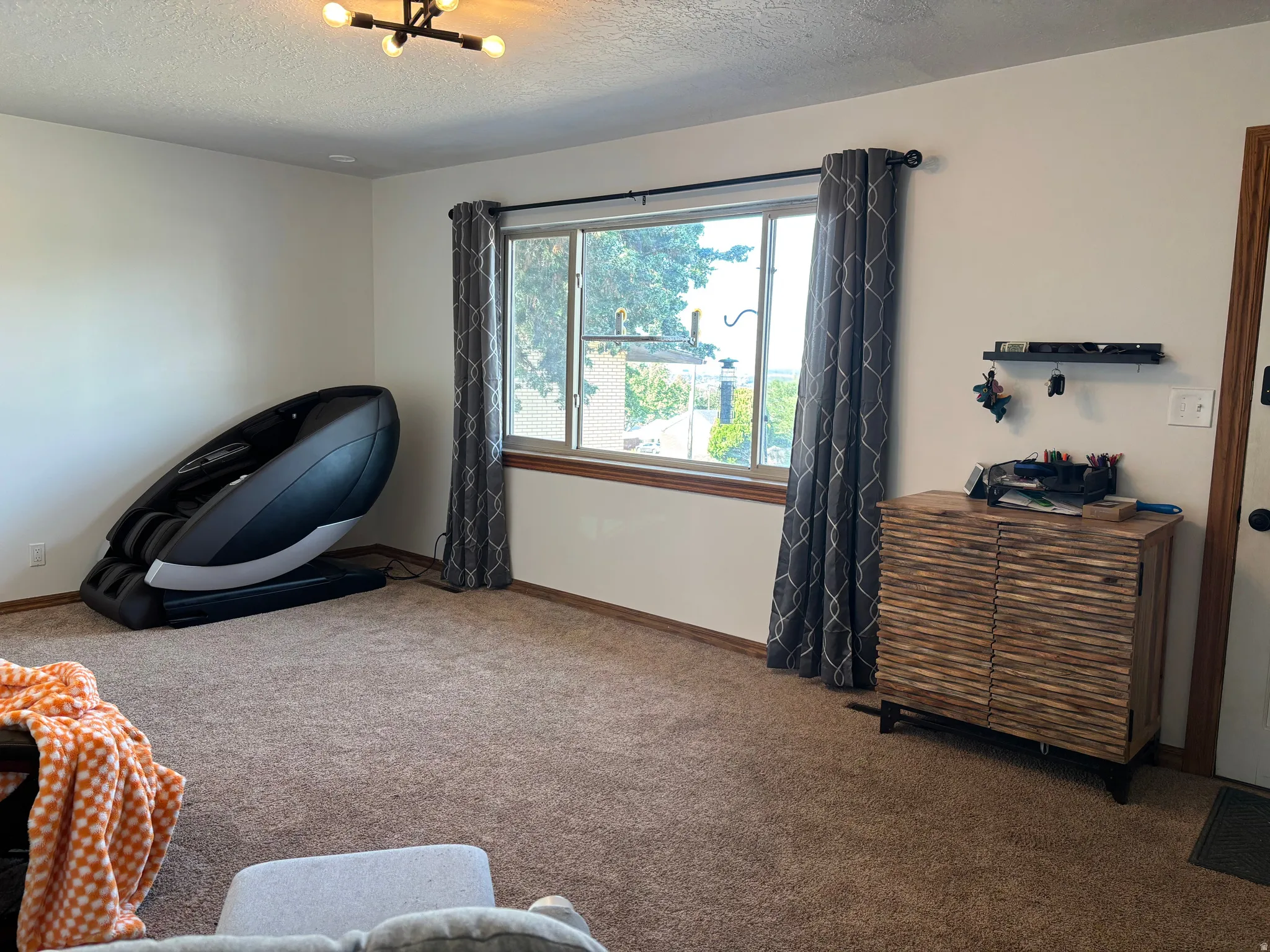 Carpeted room featuring a window with wood trim, white walls, and a modern ceiling light fixture
