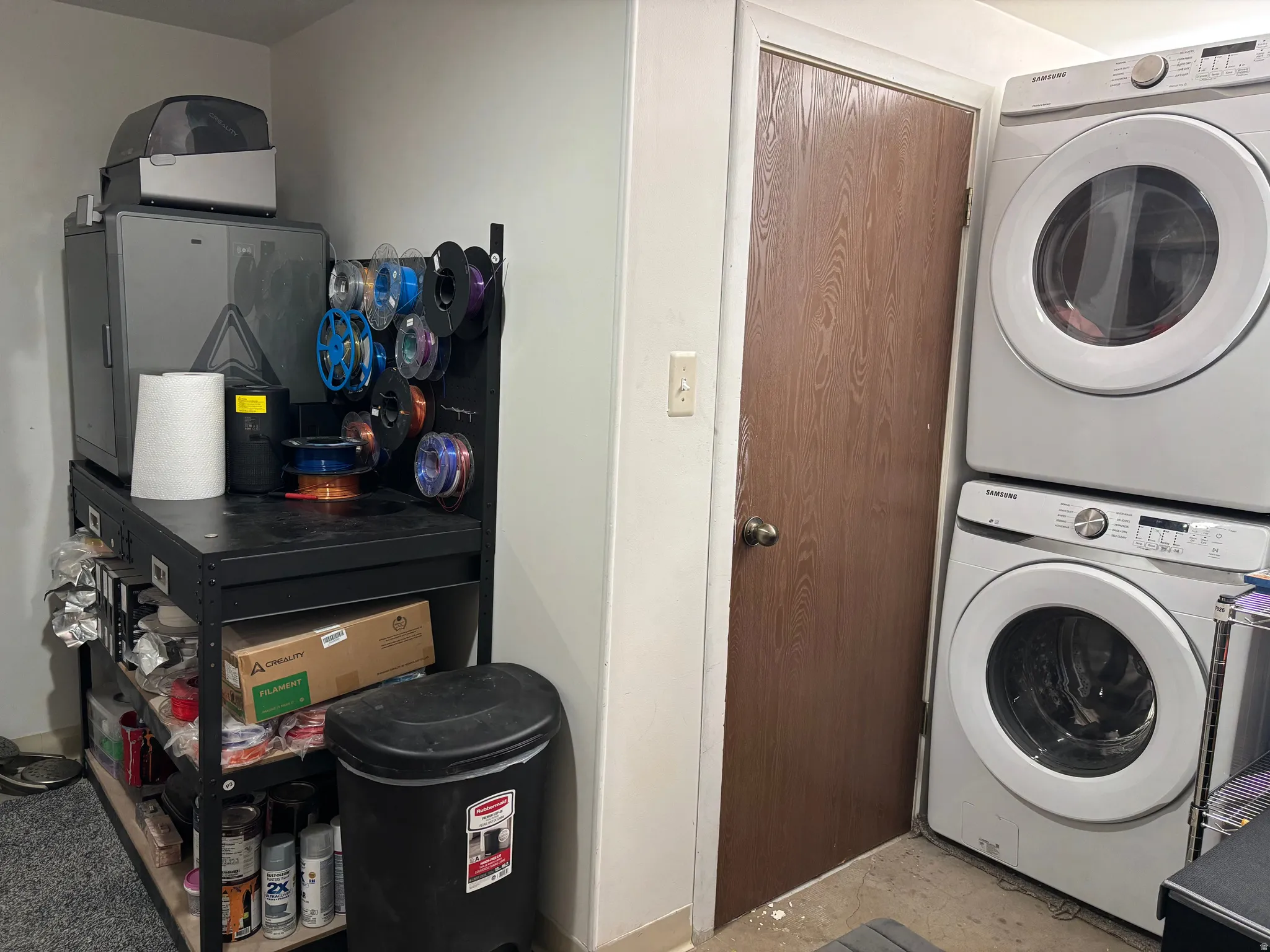 Utility area featuring a stacked washer and dryer, a wood-grain door, and a light-colored wall