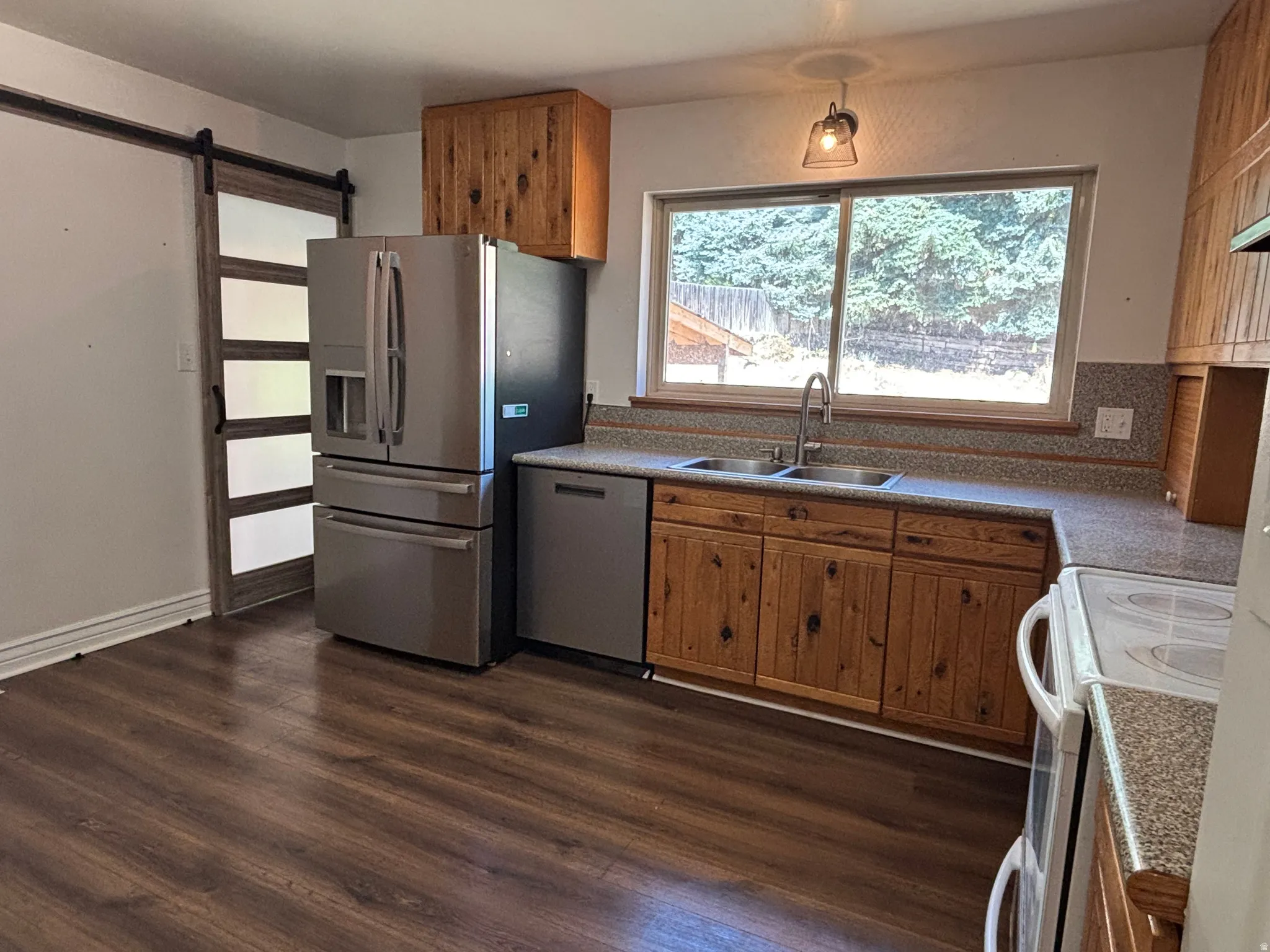 Kitchen featuring wood-finish flooring, natural wood cabinetry, stainless steel appliances, and a double basin sink