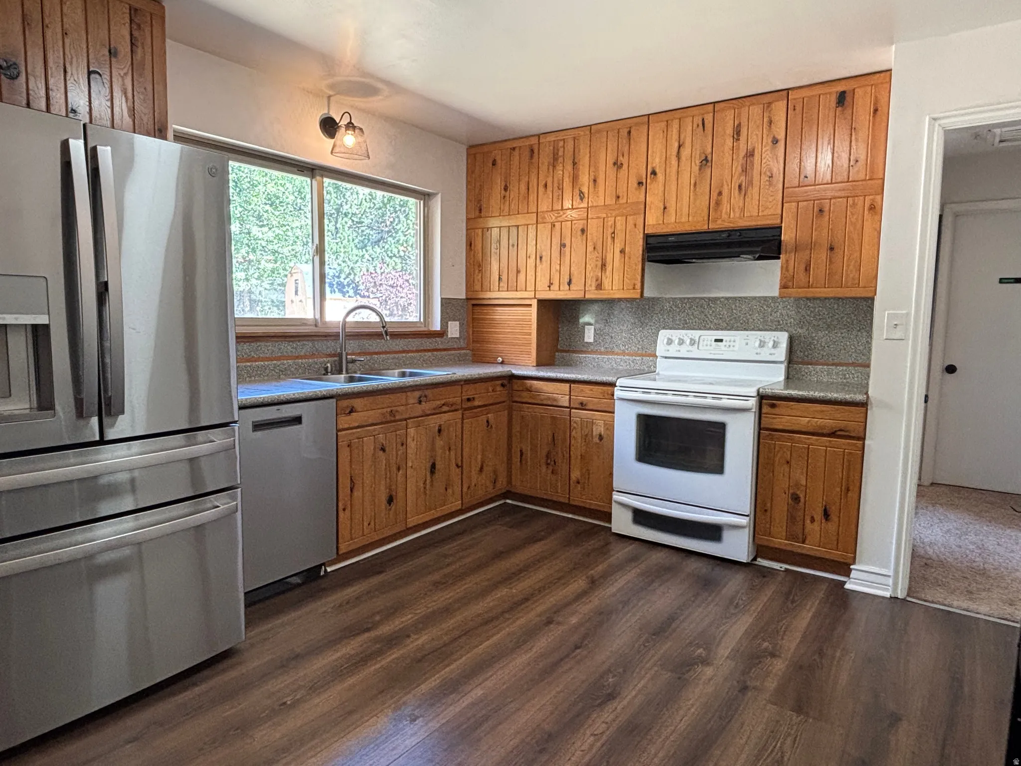 Kitchen featuring wood-finish cabinetry, stone-look countertops, and wood-finish flooring