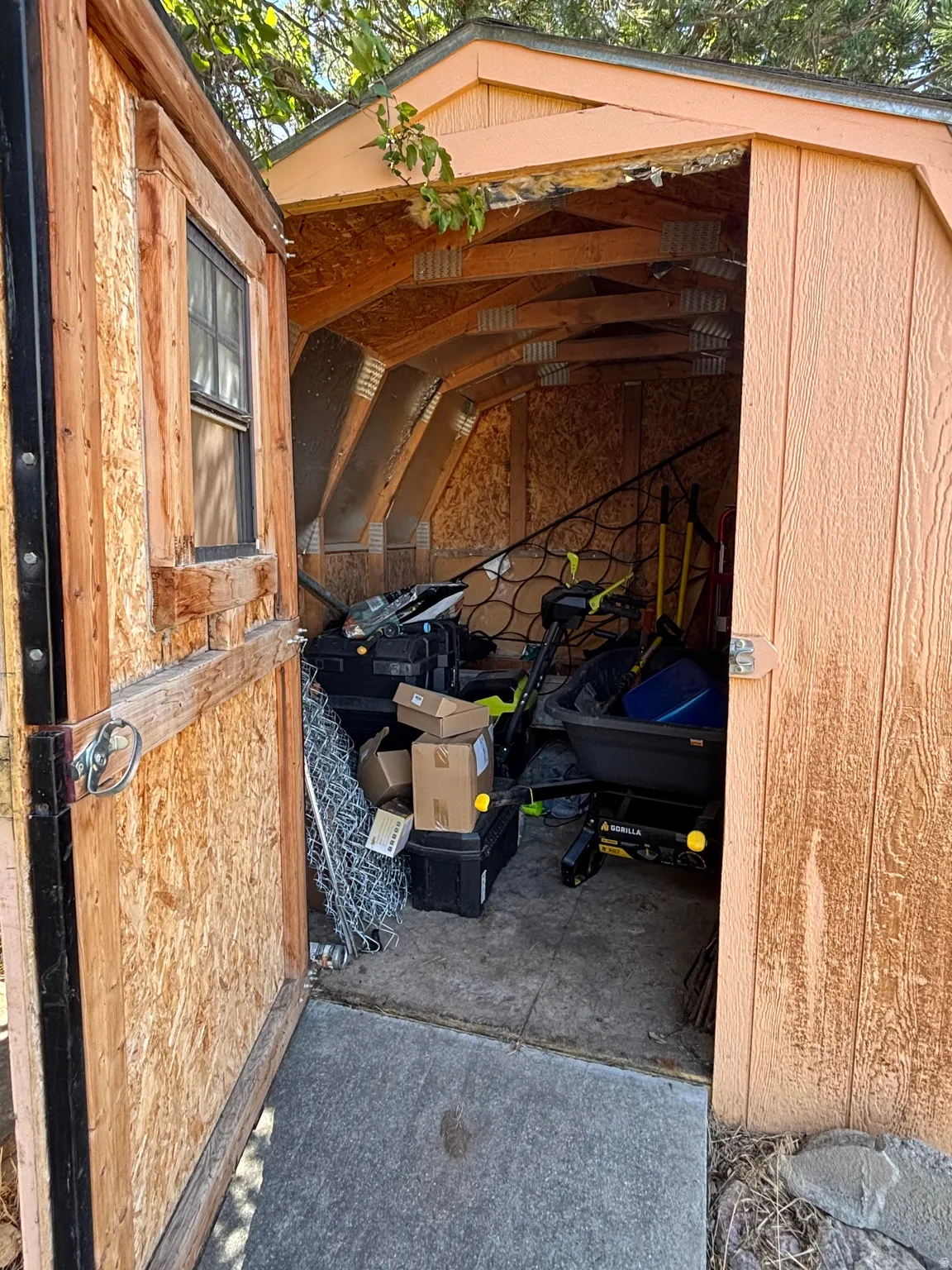 Freestanding outdoor storage shed featuring an open gabled roof structure, wood-finish paneling, and an operational window