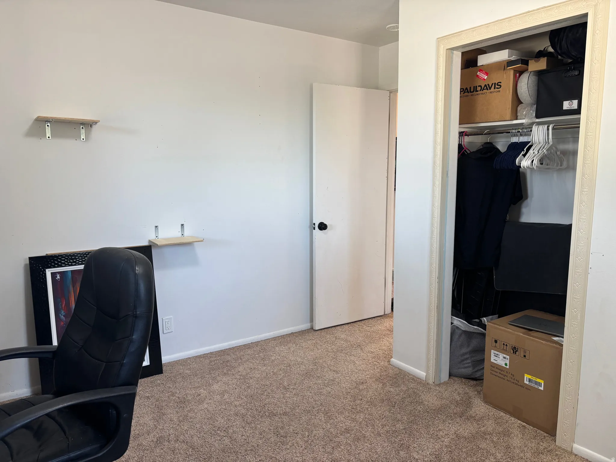 Room featuring light brown carpet flooring and a closet with a built-in hanging rod and shelving
