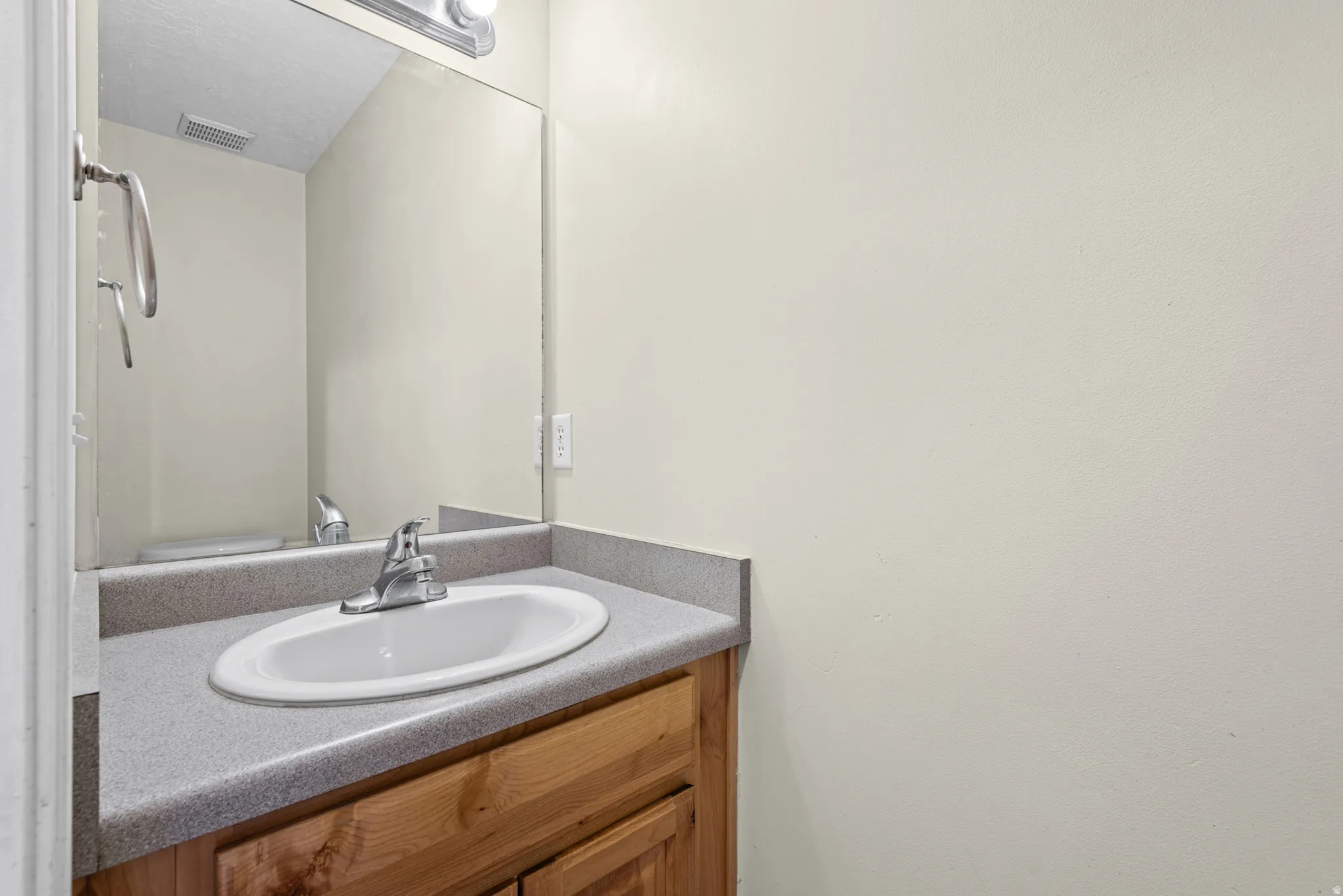 Vanity featuring a wood-finish base, integrated countertop with an oval sink, and a chrome faucet