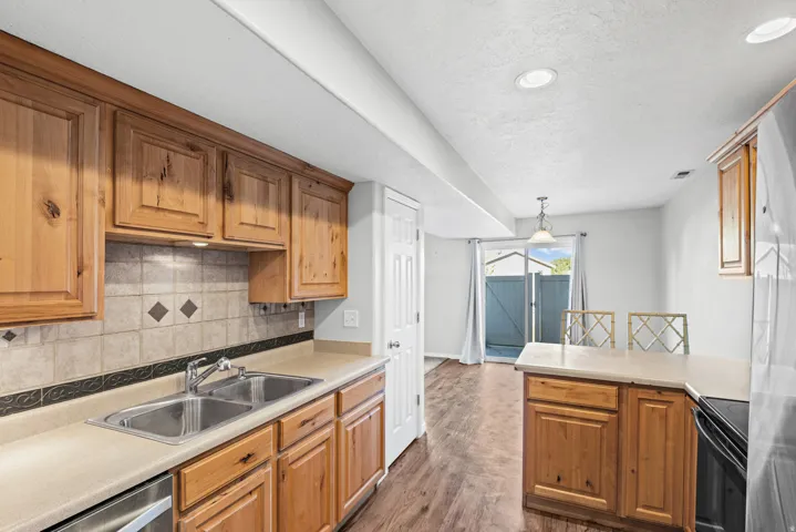 Kitchen featuring wood cabinetry, a double basin stainless steel sink, and a tiled backsplash