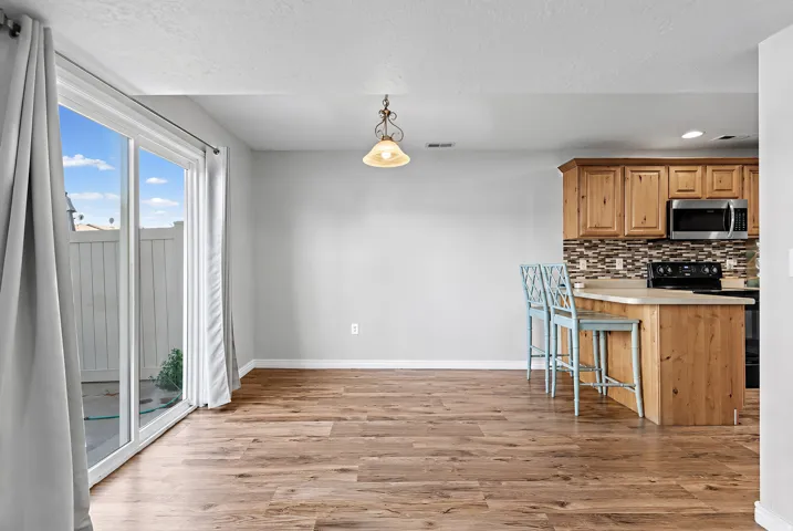 Open-concept living space featuring wood-finish flooring, a sliding glass door with exterior access, and a kitchen island with seating