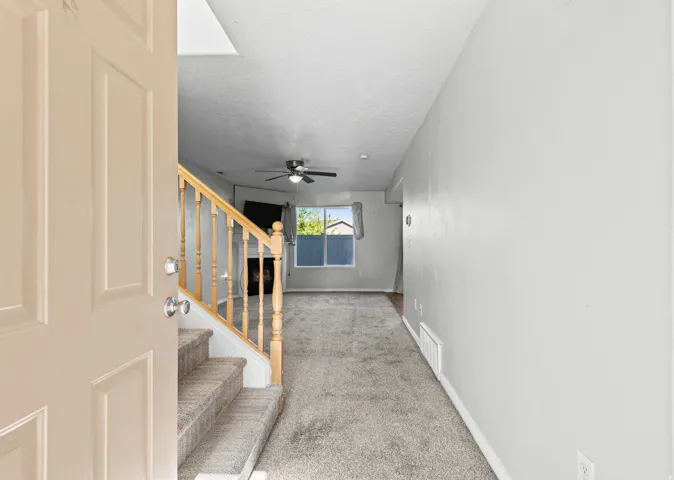 Entryway featuring a staircase with carpeted treads and natural wood banister