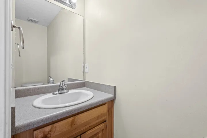 Vanity featuring a wood-finish base, integrated countertop with an oval sink, and a chrome faucet