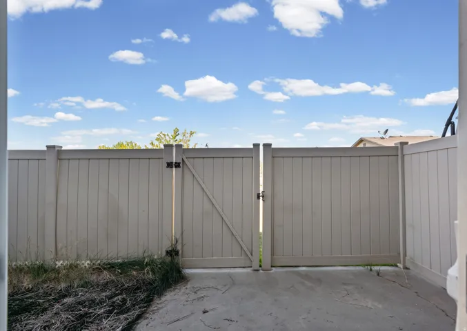 Private patio area with a light-colored privacy fence and an access gate