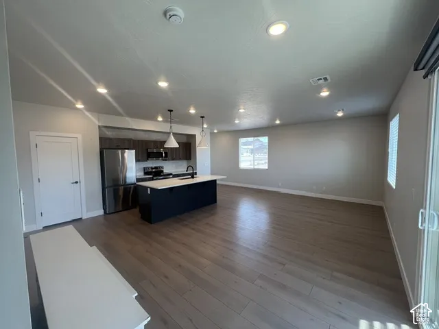 Open-concept living space featuring wood-finish flooring, recessed lighting, and a modern kitchen island with pendant lights