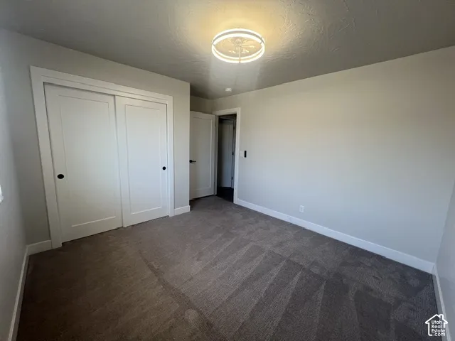 Bedroom with neutral wall paint, textured carpet flooring, and white trim