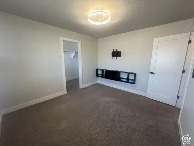 Carpeted room featuring a ceiling-mounted light fixture, white trim, and a built-in floating media shelf