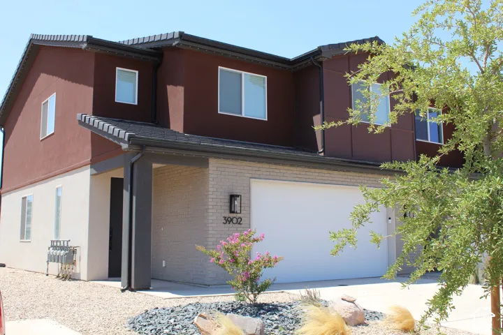 Contemporary two-story residence featuring a two-tone stucco and brick facade with dark trim