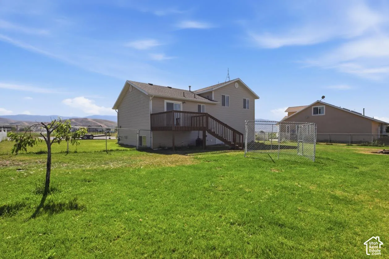 The property features a spacious backyard with a deck and mountain backdrop