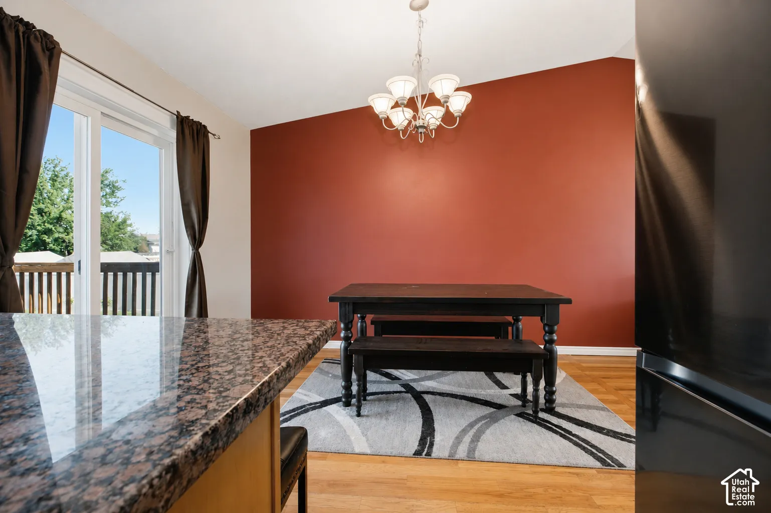 Spacious dining area featuring hardwood-finish flooring, a contemporary chandelier, and direct access to an outdoor deck through sliding glass doors