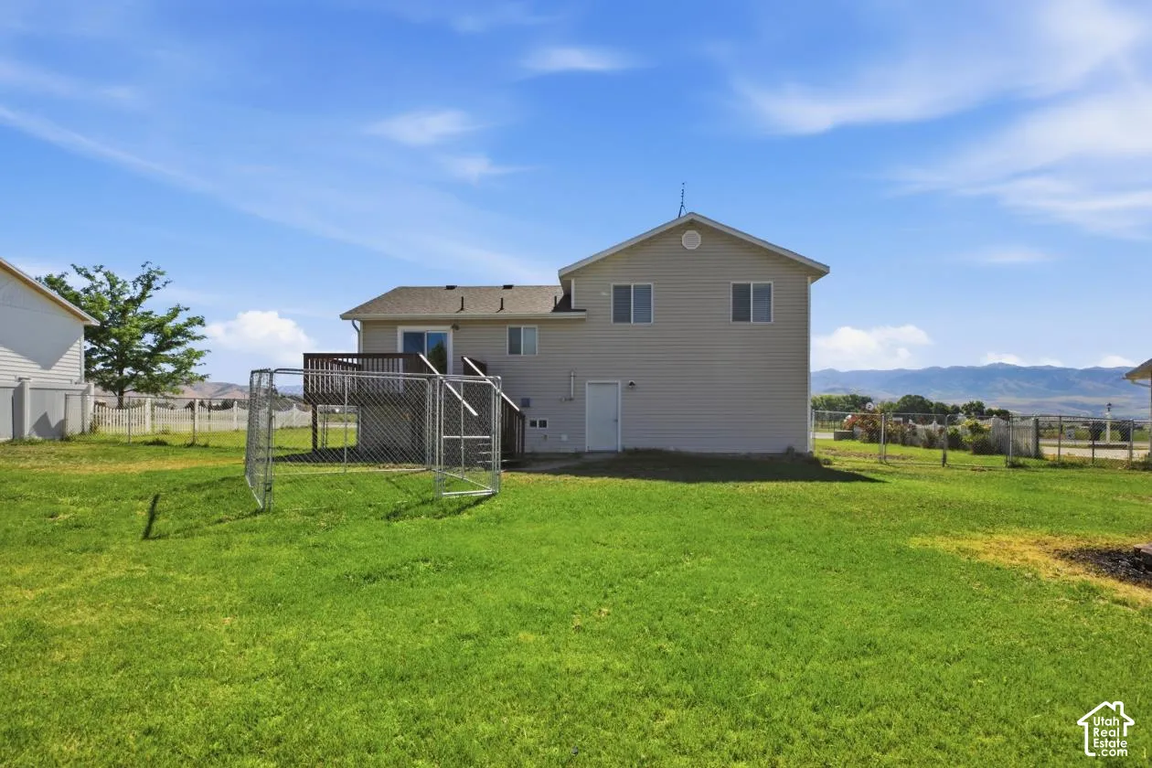 Expansive green lawn with a two-story residence featuring light-colored siding and a rear deck