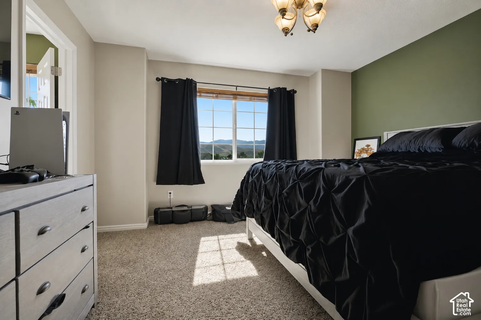 Carpeted bedroom featuring a large window with mountain scenery, a two-tone wall treatment, and an ornate ceiling light fixture