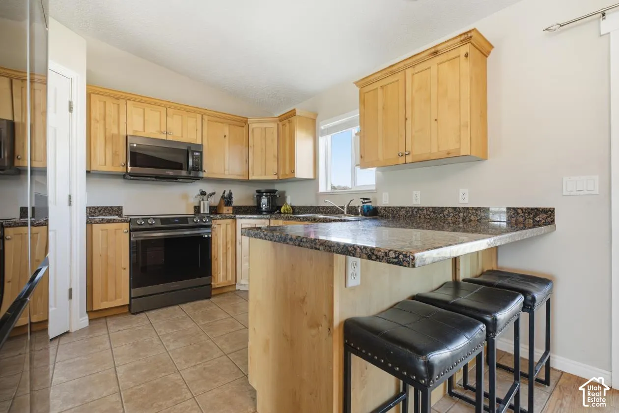Kitchen featuring wood cabinetry, dark granite countertops, and tile flooring
