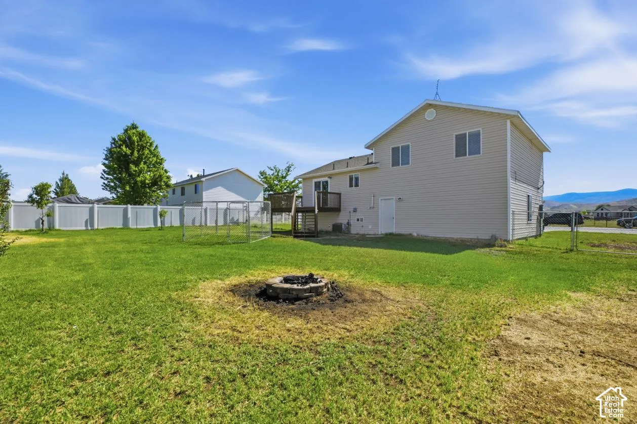 Expansive backyard featuring a built-in fire pit, a white vinyl privacy fence, and a chain-link enclosure
