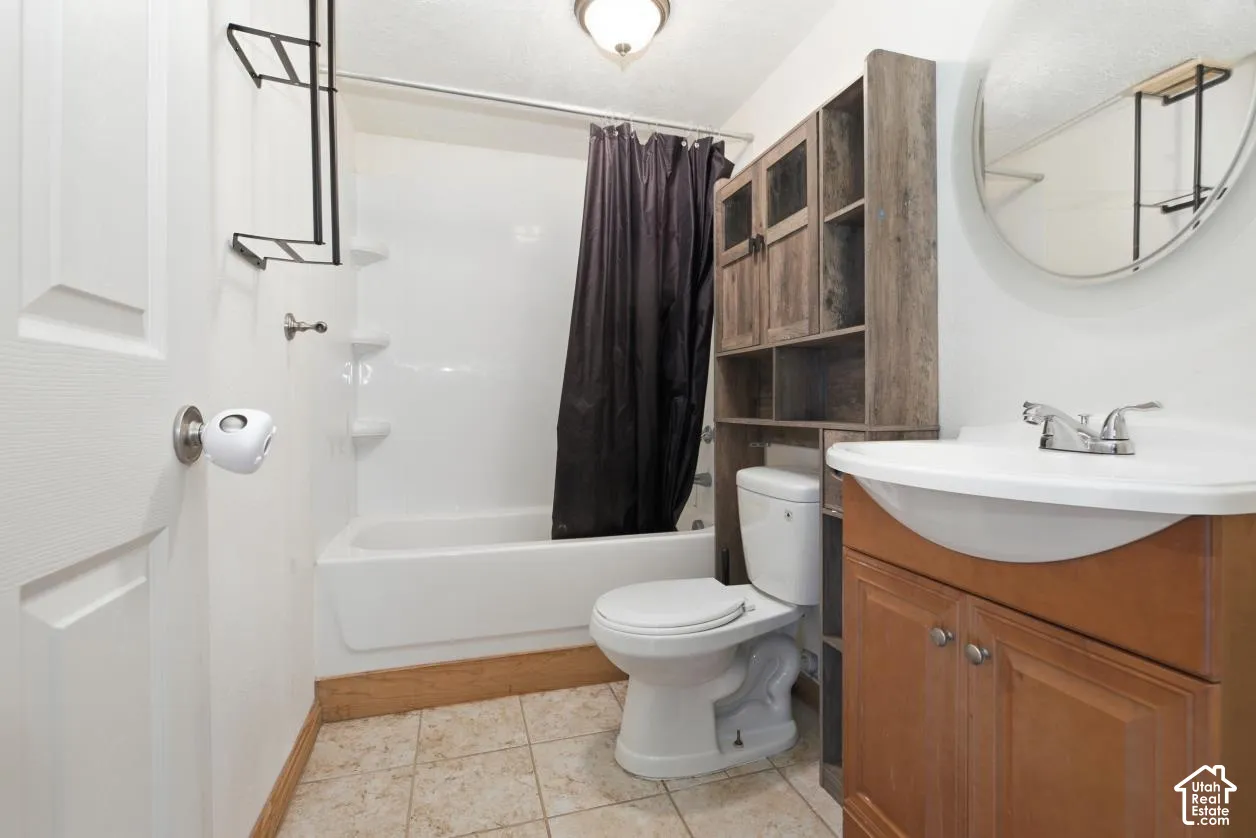 Bathroom featuring a white bathtub, toilet, and a wood-finish vanity with an integrated sink