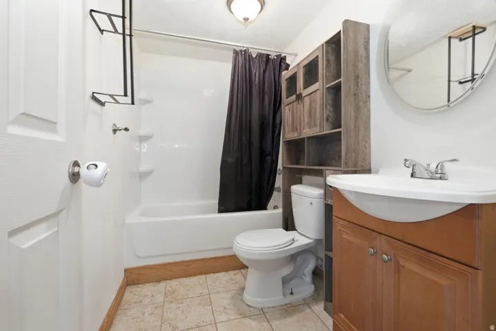 Bathroom featuring a white bathtub, toilet, and a wood-finish vanity with an integrated sink