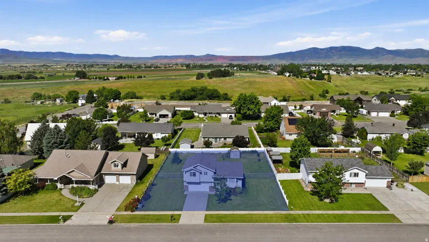 Aerial perspective highlighting a single-family residence with an attached garage, front yard, and backyard