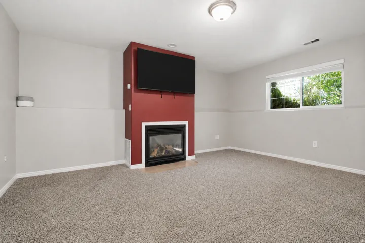 Living area featuring a floor-to-ceiling accent wall with a built-in fireplace and integrated media space