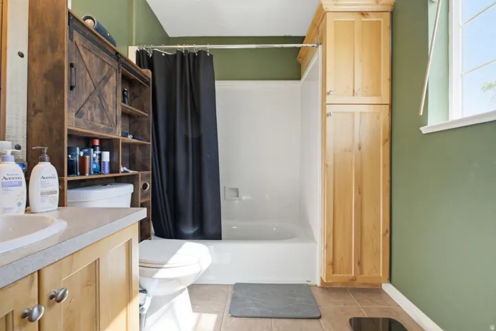 Bathroom featuring a white tub/shower combination, a light-colored vanity with a built-in sink, and a window with white trim