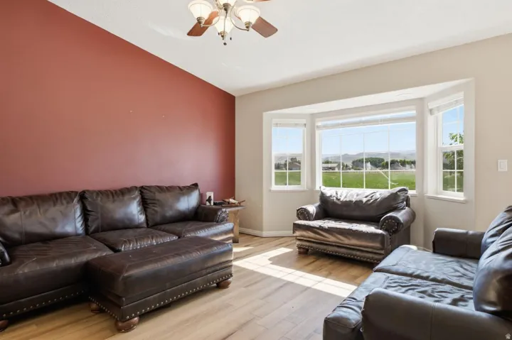 Bay window offering extensive exterior views, wood-finish flooring, vaulted ceiling with ceiling fan, and a prominent accent wall