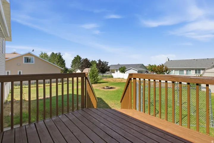 Expansive outdoor deck featuring wood-finish decking and railings, with a grassy yard below