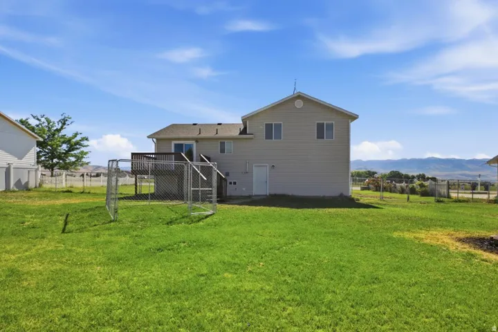 Expansive green lawn with a two-story residence featuring light-colored siding and a rear deck