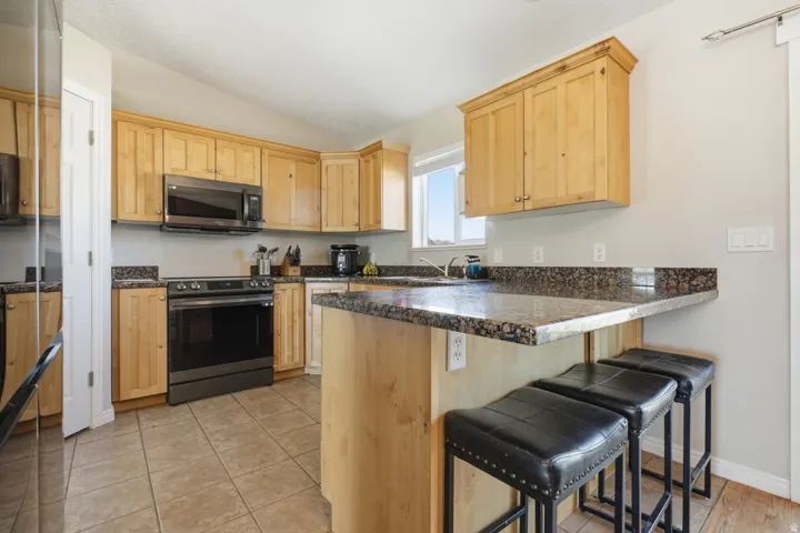 Kitchen featuring wood cabinetry, dark granite countertops, and tile flooring