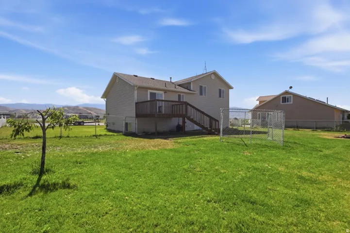 The property features a spacious backyard with a deck and mountain backdrop