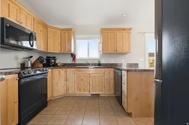 Kitchen featuring abundant light wood cabinetry, stone-finish countertops, and stainless steel appliances
