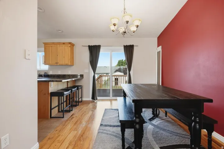 Dining area featuring wood-finish flooring and a red accent wall