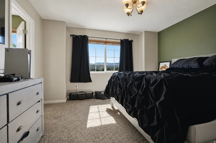 Carpeted bedroom featuring a large window with mountain scenery, a two-tone wall treatment, and an ornate ceiling light fixture