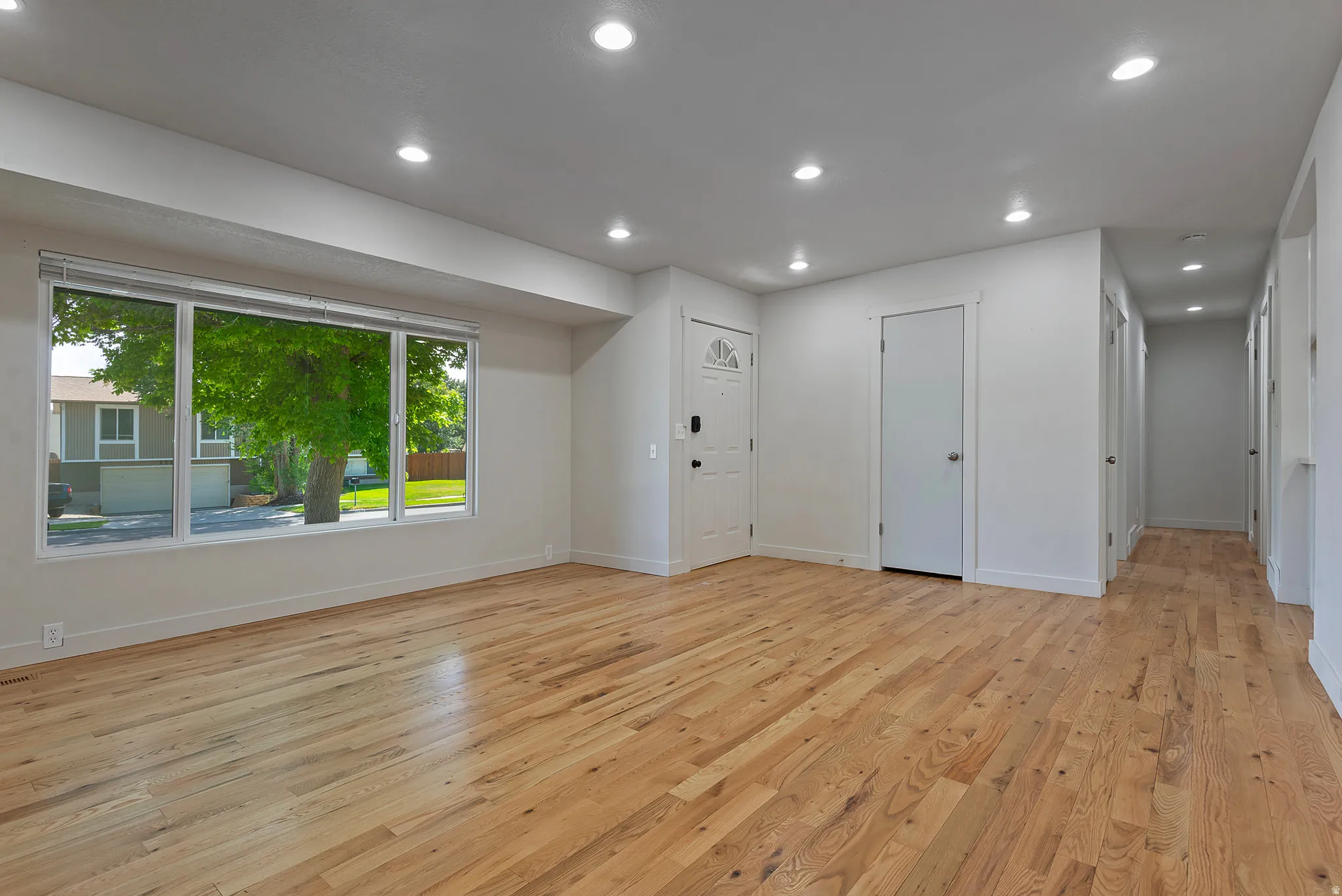 Spacious living area featuring wood-finish flooring, recessed lighting, and a large multi-pane window